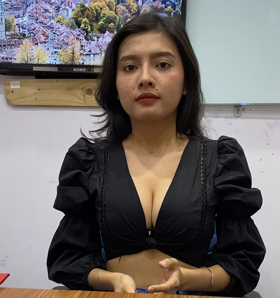 An elegant woman in a black top sitting at a desk, exuding the allure of a KL escort girl.