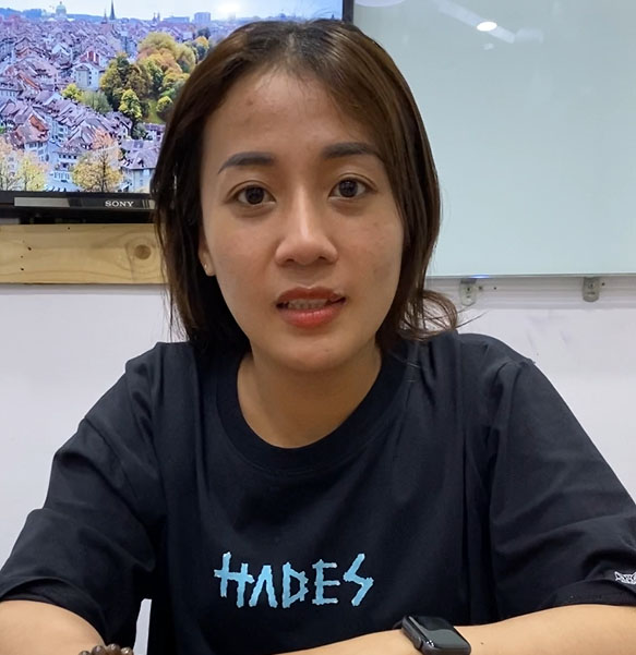 A woman sitting at a desk in Kuala Lumpur, wearing a t-shirt that says Hades.