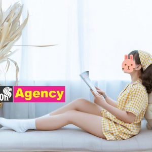 A girl is sitting on a bed reading a book in 707.