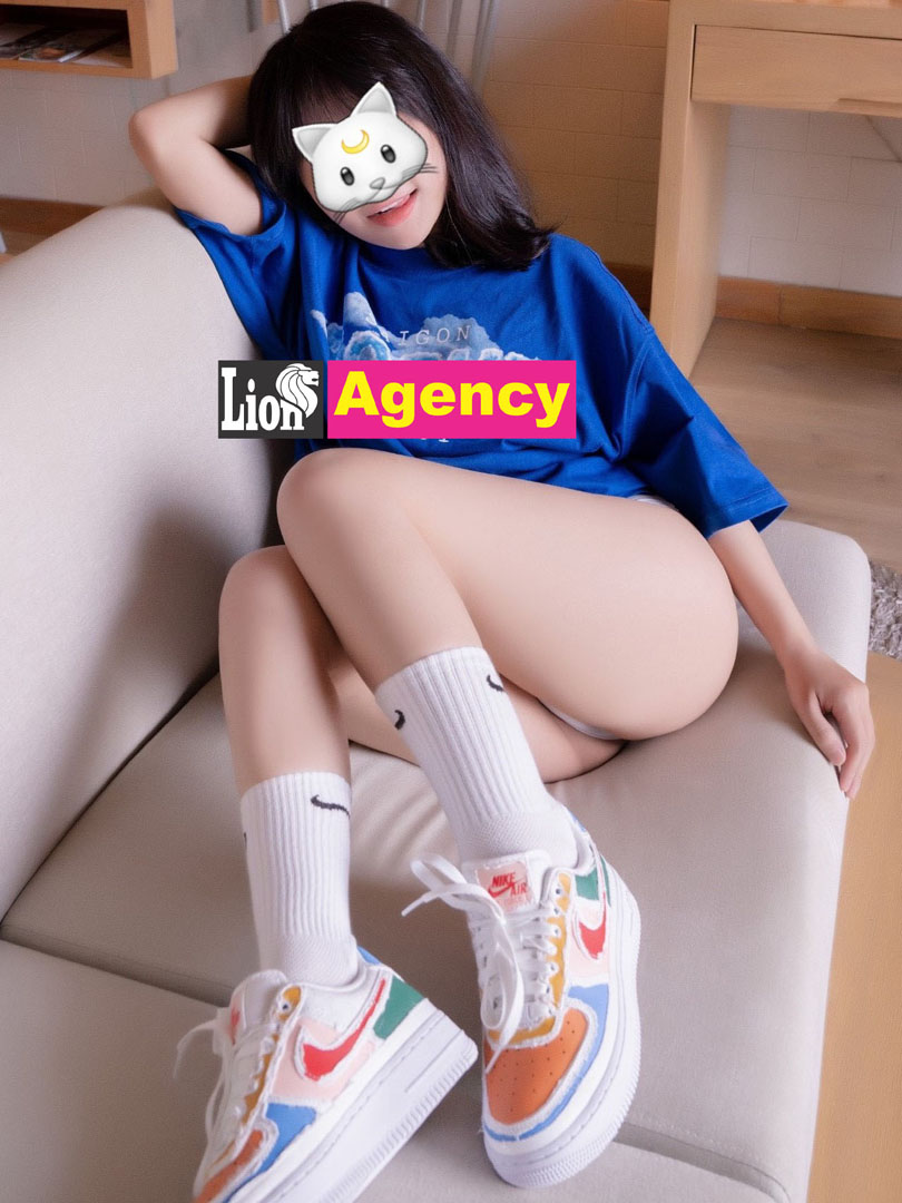A 707 escort girl sitting on a couch with sneakers on her feet.