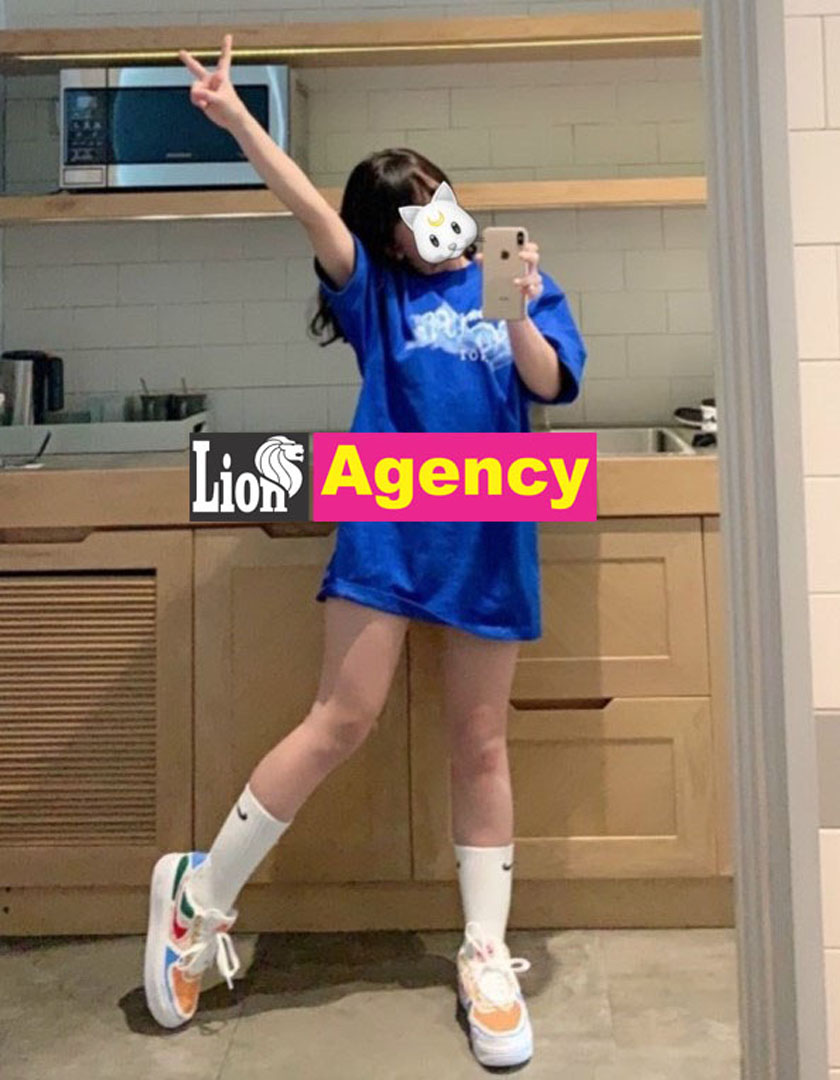 A 707 escort, wearing a blue shirt, is posing in front of a mirror.