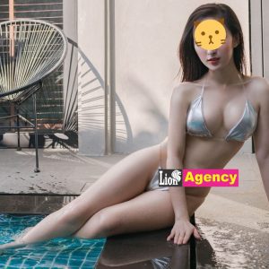 A woman in a bikini, known as an 799, confidently poses next to a pool.