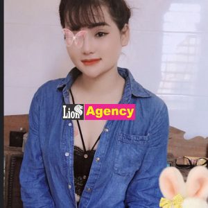 A girl in a blue shirt is posing with a bunny stuffed animal.