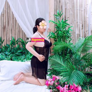 A woman in a black dress posing on a bed, possibly as a 540 or kl escort.